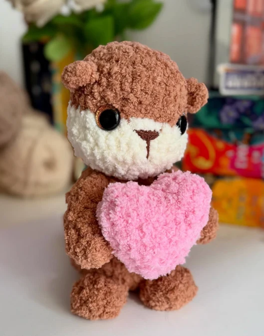 A crochet otter Nicole made, holding a pink heart